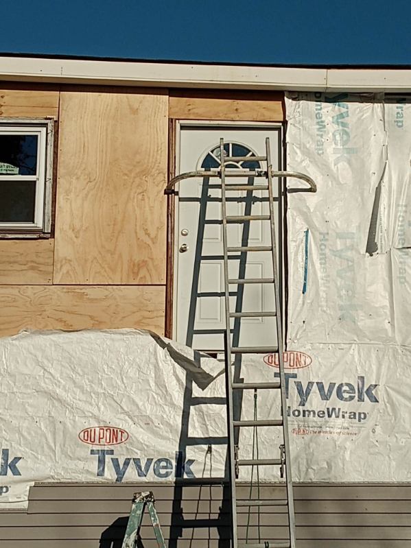 A house under construction with a new door and window set into fresh house wrap